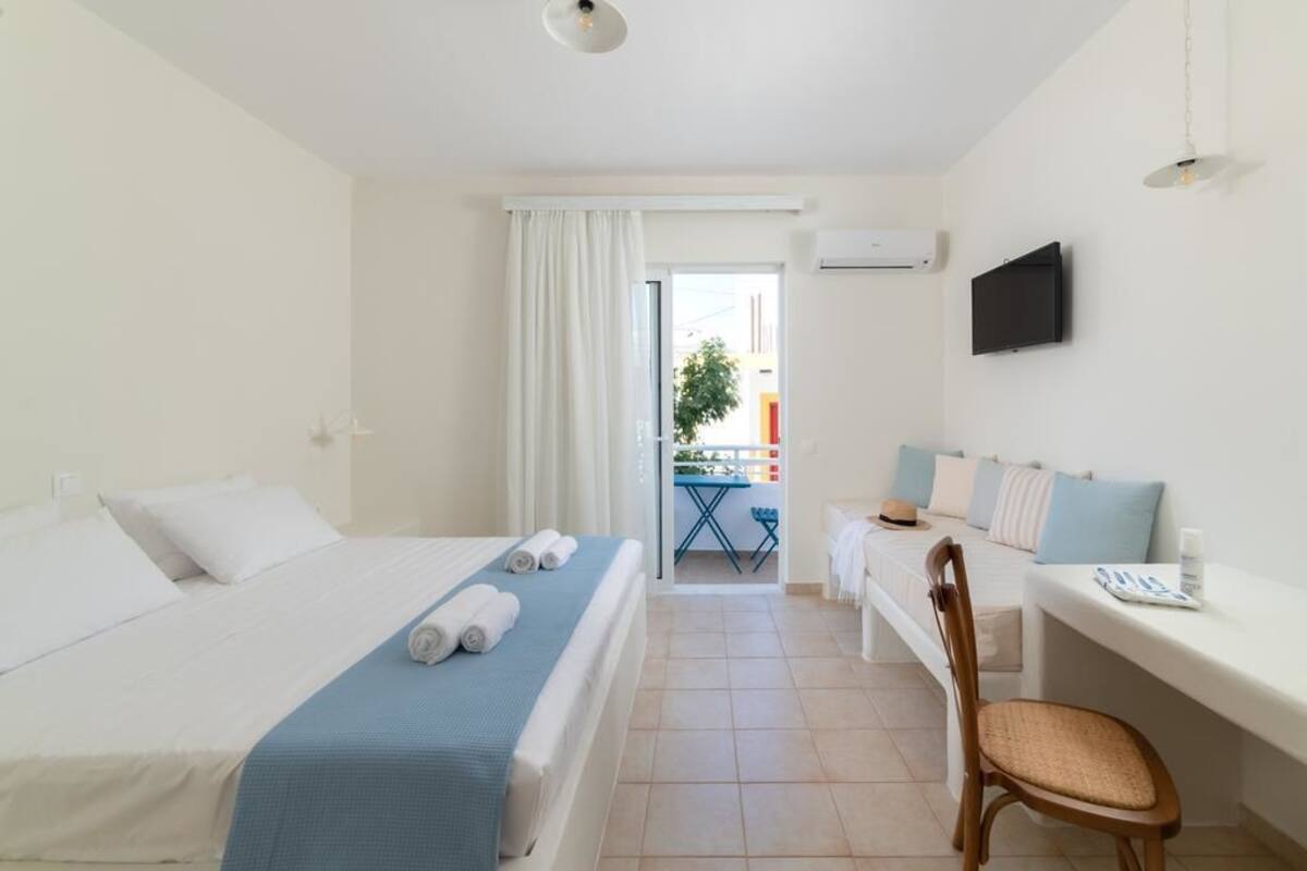 A hotel room with a bed, a desk, a chair, and a TV.