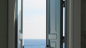 A window with an open door, revealing a view of the sea. - Stegna Akti (Rhodes)