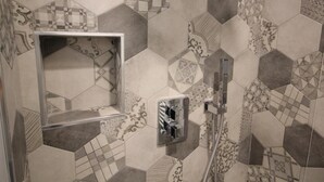 A bathroom with a geometric tile pattern, a glass shower enclosure, and a modern faucet.