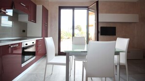 A modern kitchen with a dining area, featuring a large window and a flat-screen TV mounted on the wall.