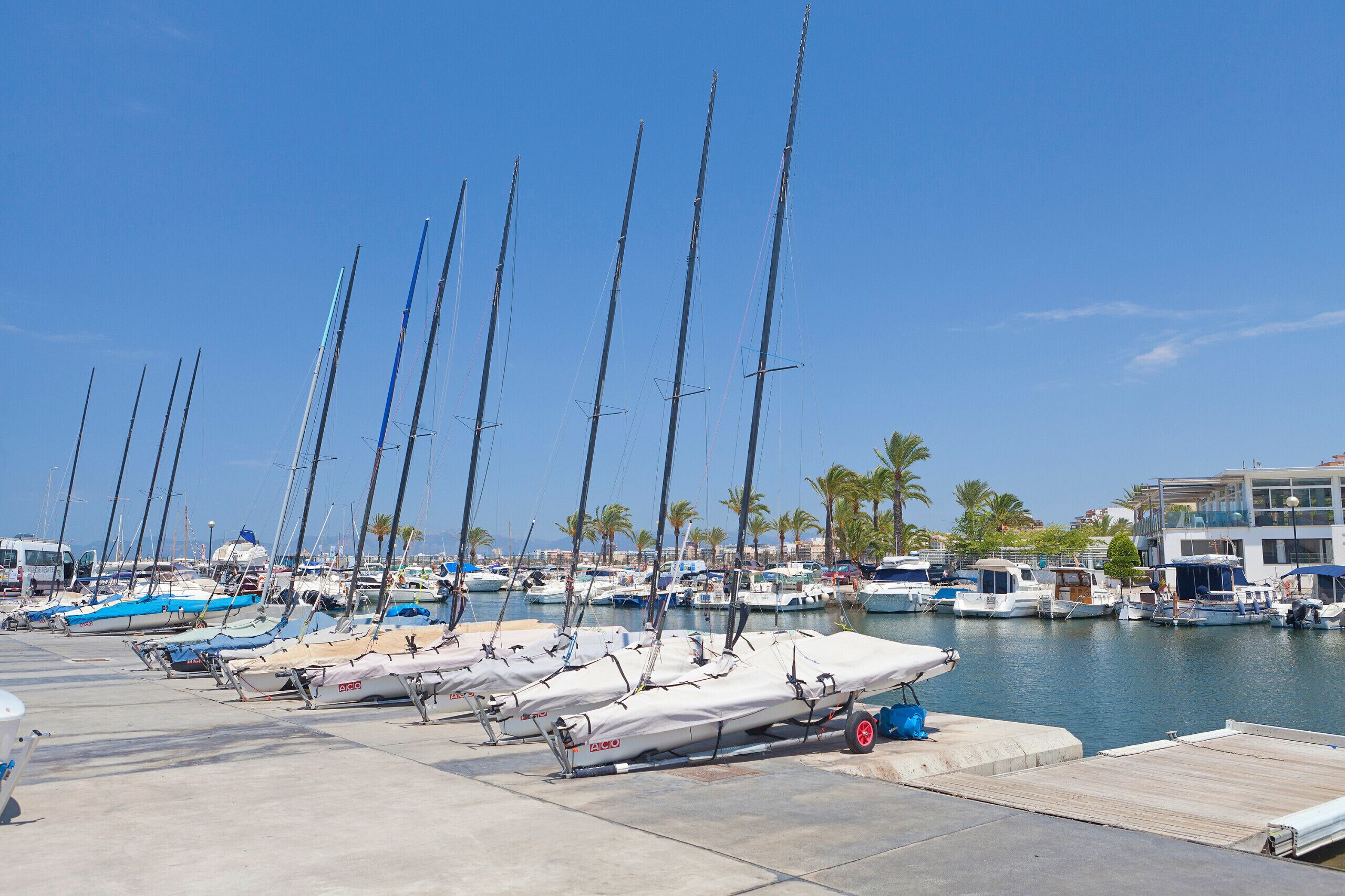 Un port de plaisance où sont amarrés de nombreux bateaux, un ciel dégagé et, au fond, un bâtiment doté d’un balcon.