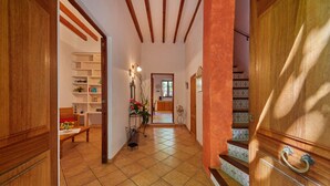 A hallway with wooden floors, a staircase with patterned tiles, and a view into a dining area with a table and chairs. - Casa Fortuny in Soller (Sóller)