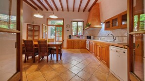 A kitchen with wooden cabinets, a dining table with chairs, and a dishwasher. - Casa Fortuny in Soller (Sóller)