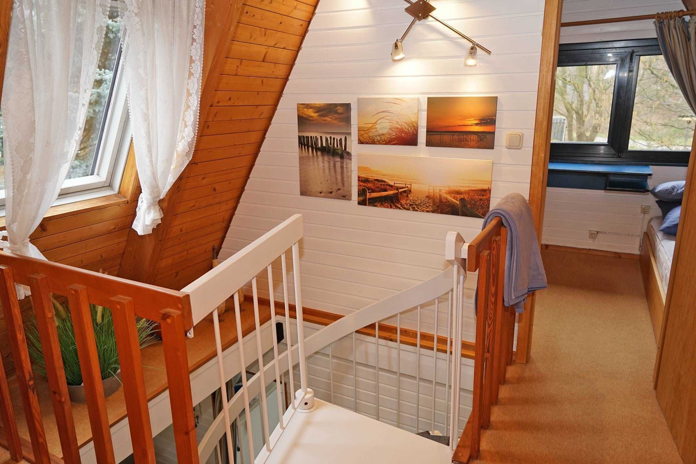 L’intérieur d’une cabine avec un escalier en bois, un lit superposé et un mur orné de tableaux.