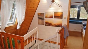 Een vakantiehuisje interieur met een houten trap, een stapelbed en een wand met ingelijste foto's.