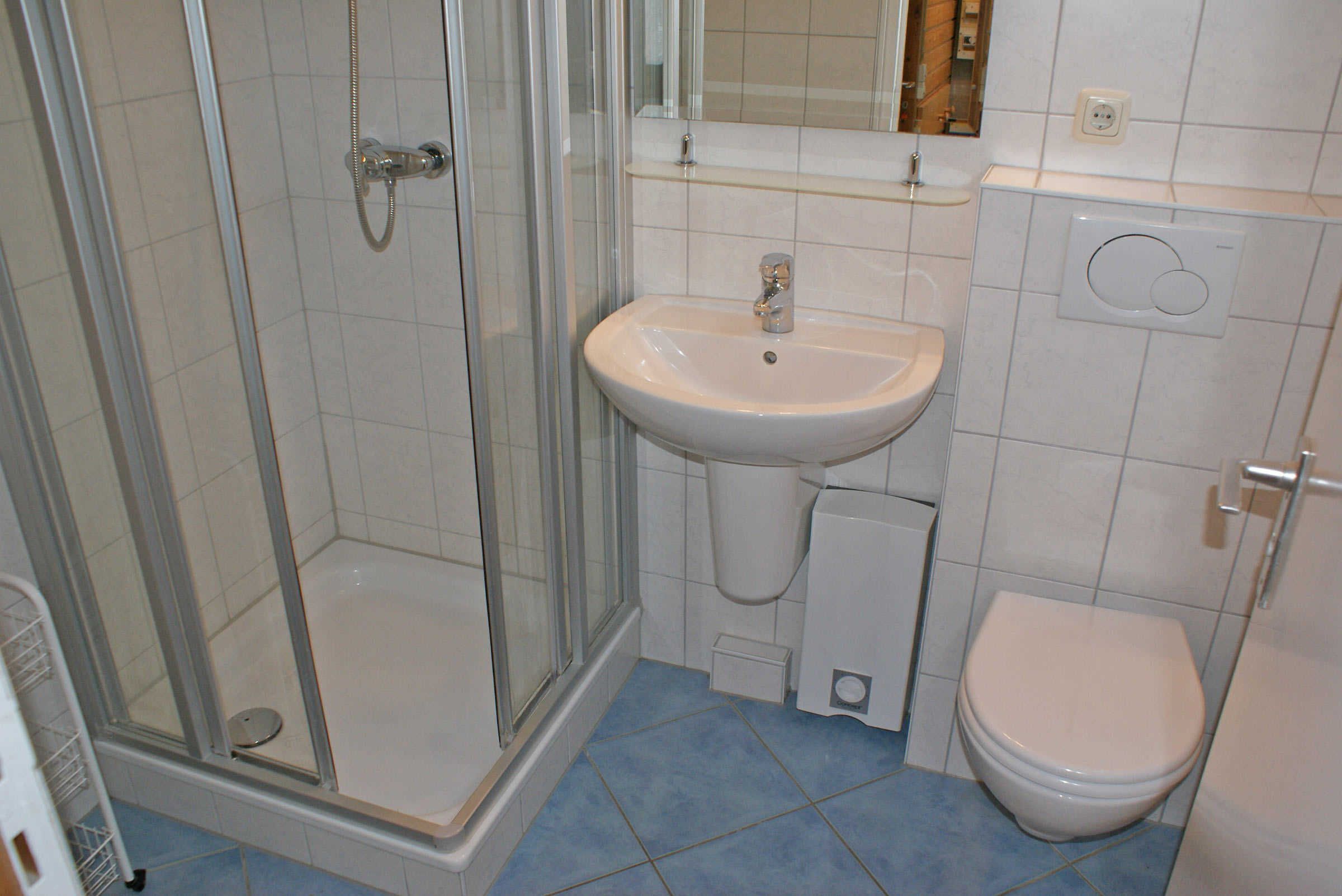 Un baño con ducha de vidrio, lavamanos y retrete.