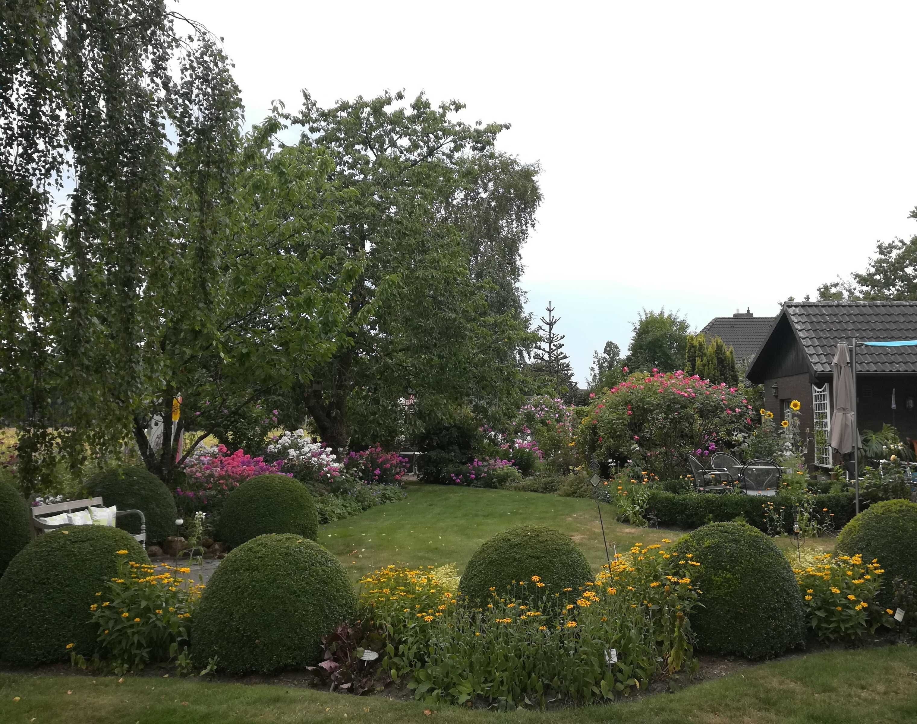 A well-maintained garden with various flowering plants and neatly trimmed hedges.