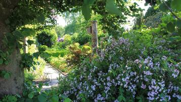 Ein Gartenweg, umgeben von üppigem Grün und blühenden Pflanzen.