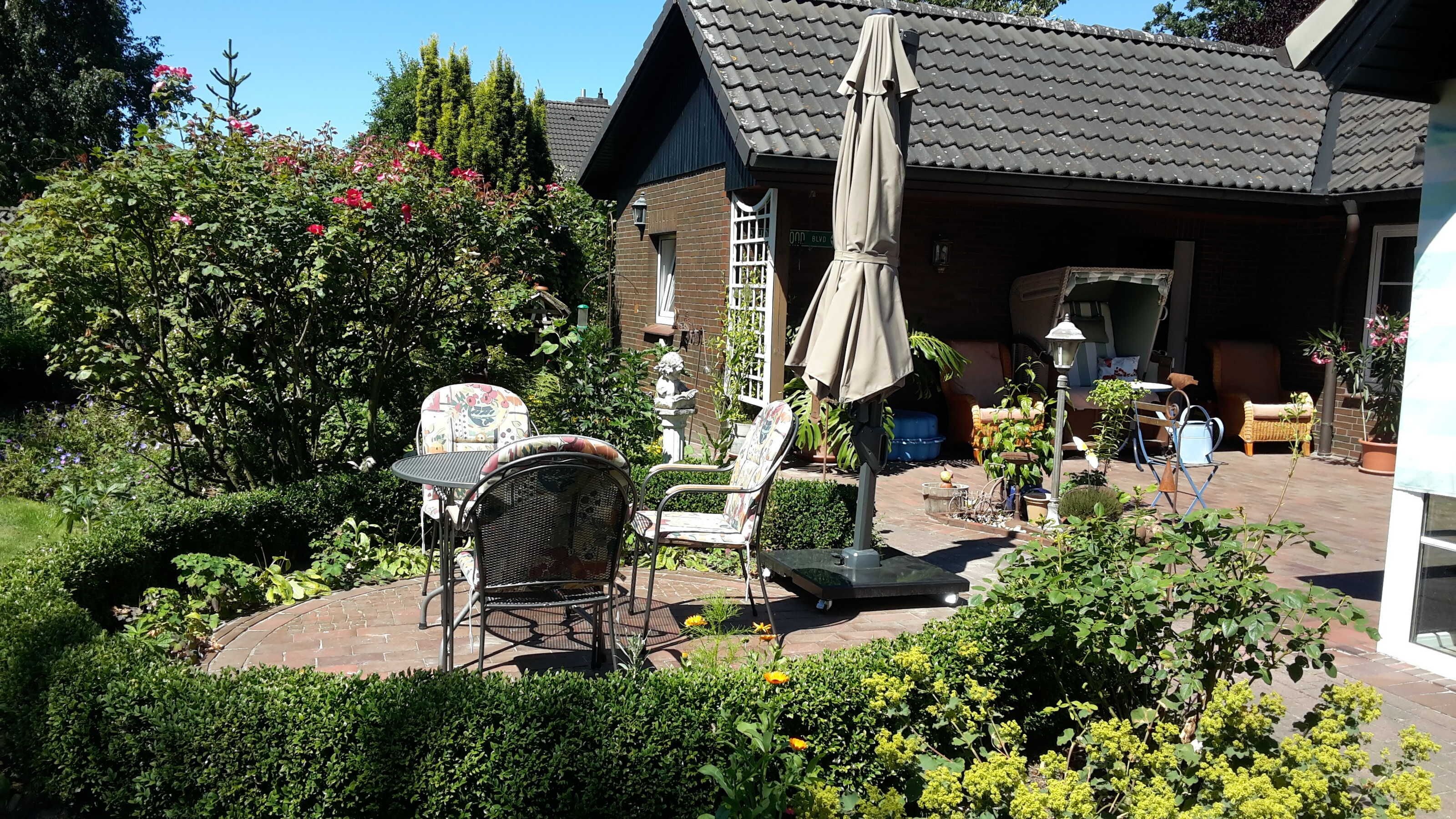Uma área de pátio com móveis de exterior, um jardim e uma casa com telhado em telhas.
