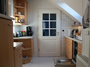 A compact kitchen with wooden cabinets, a coffee maker, and a dishwasher.