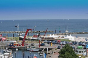 A marina with boats, a red crane, and a beach area with tents and cars.