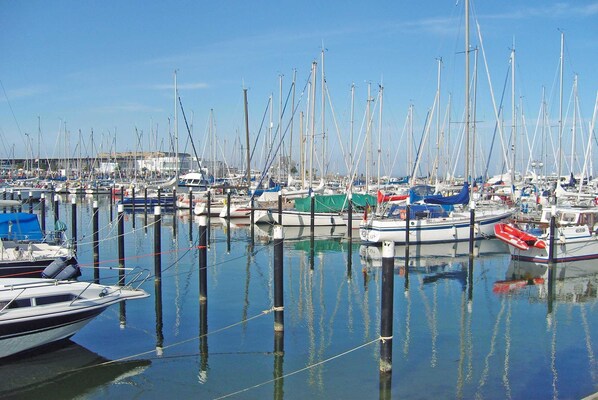 A marina with numerous boats docked, calm water, and clear skies.
