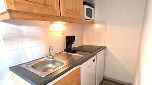 Una cocina compacta con un lavamanos, una cafetera y un microondas.
