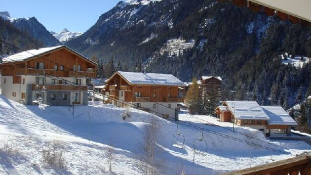 A snow-covered mountain resort with wooden buildings and ski slopes.
