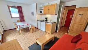 Un espacio habitable compacto con kitchenette, zona de comedor y sofá.
