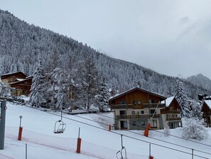 Et snedækket bjælkehytte med flere træhytter, skilift og skibakke.