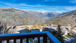 Eine gebirgige Landschaft mit einem Dorf und blauem Himmel.