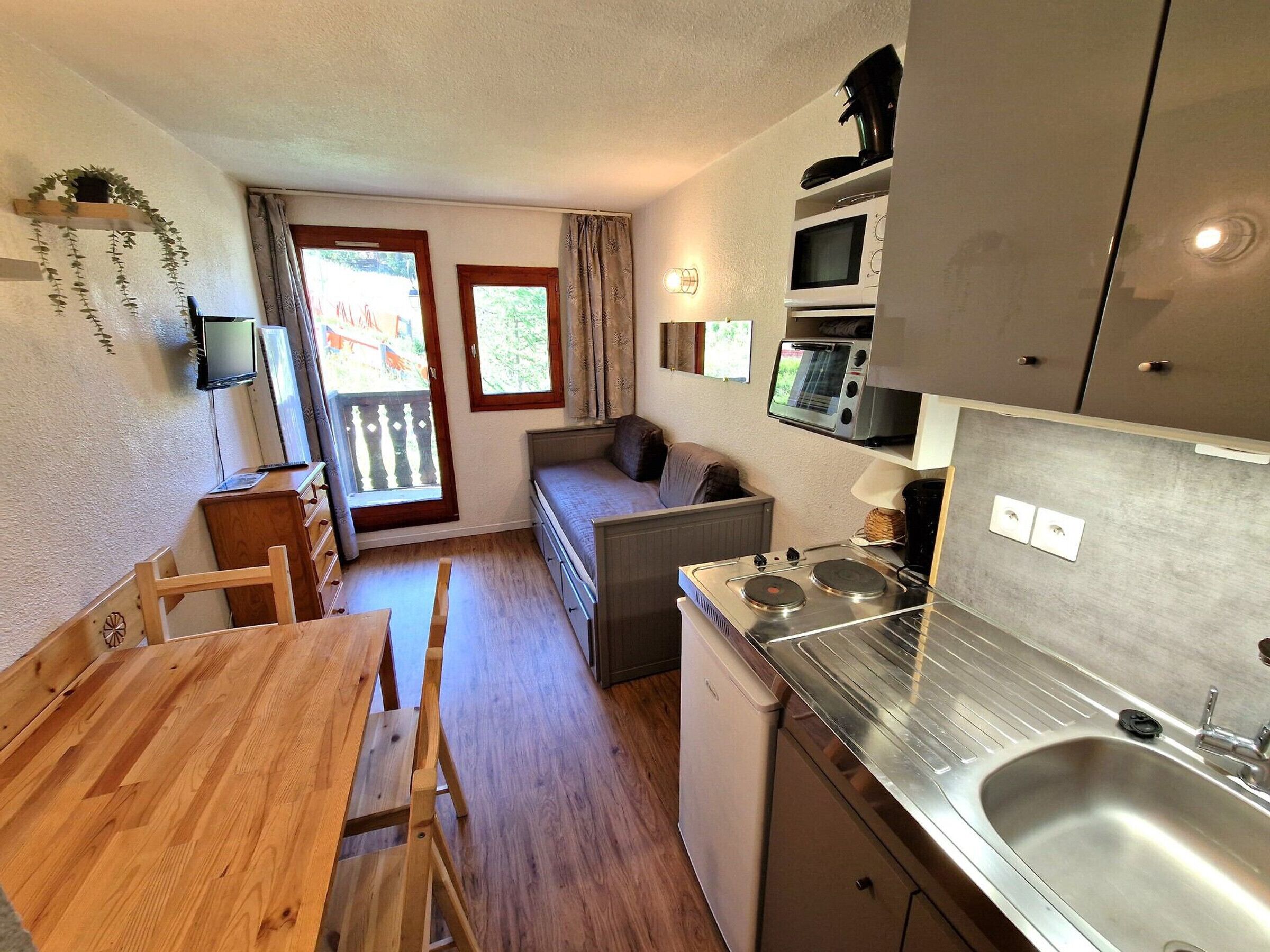 Une cuisine compacte comprenant une table à manger, un canapé et un four encastré.