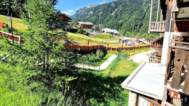 A mountain lodge with a wooden exterior, a balcony, and a view of the surrounding forest and mountains. - Renovated studio for 2-3 in Valfréjus, balcony and slope view (Valfréjus)