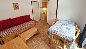 A compact room with a sofa, a dining table, and a kitchenette. - Valfréjus: 2-room + cabin, central location, 4/6 people (Valfréjus)