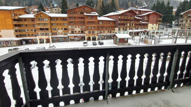 A snow-covered mountain town with wooden buildings, including a hotel with balconies and a ski resort in the background. - Valfréjus: 2-room + cabin, central location, 4/6 people (Valfréjus)