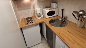 A compact kitchen with a built-in stove, a microwave, a coffee maker, and a sink. - Cozy 2-Room Apartment for 4/6 People, 32m² - Ski-in/Ski-out, Close to Village Center (Valfréjus)