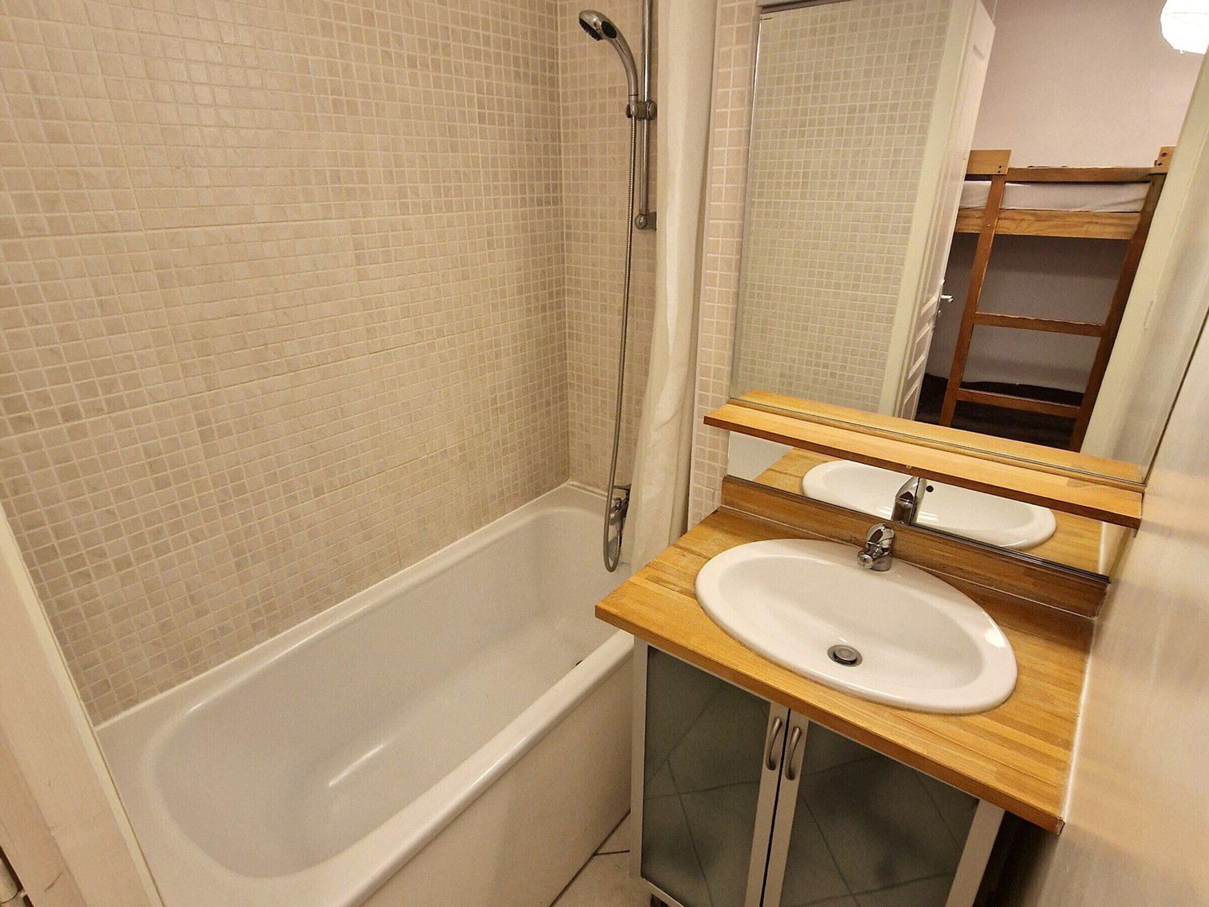 A bathroom with a bathtub, a sink, and a mirror.
