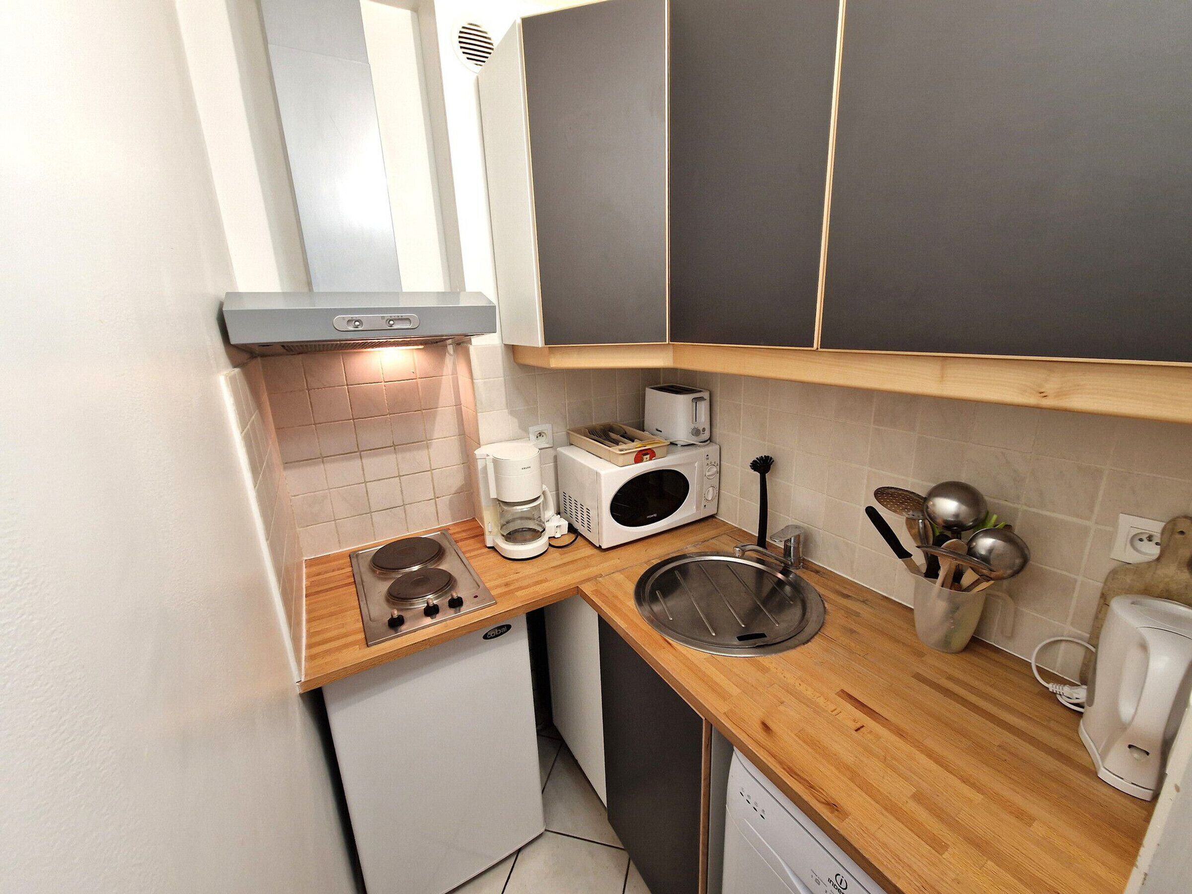A compact kitchen with a built-in oven, a coffee maker, a microwave, and a sink.