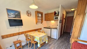 A compact kitchen with wooden cabinets, a microwave, and a refrigerator.