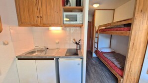 A compact kitchen with wooden cabinets, a microwave, and a refrigerator.