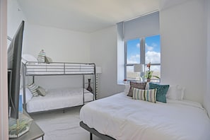 Habitación de hotel con dos camas, televisión y ventana con vistas al cielo.