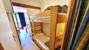 A bunk bed room with a wooden floor and a door leading to another room. - Charming studio for 2-3 people with balcony in Valfréjus (Valfréjus)