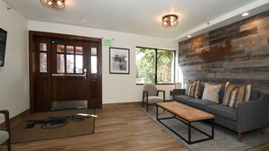 A lobby with a wooden floor, a gray sofa with striped pillows, a wooden coffee table, and a door marked "EXIT". - Main Street/Town Lift, Pool, Hot Tubs, Location, Comfort, Value, A/C, Fireplace (Park City)