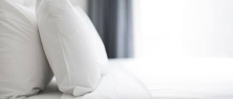 A neatly made bed with white bedding and pillows.