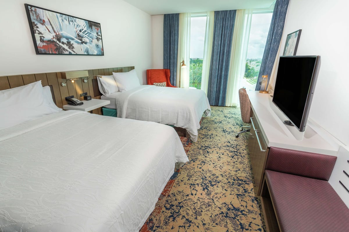 A hotel room with two beds, a TV, a desk, and a chair.