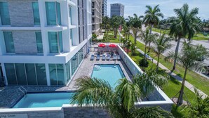 A modern hotel with a rooftop pool, sun loungers, and palm trees. - Hilton Garden Inn West Palm Beach I95 Outlets (West Palm Beach)