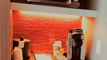 Un angolo cottura funzionale con microonde, macchina del caffè e mini-frigorifero.