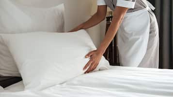A person adjusting a white pillow on a bed in a hotel room.