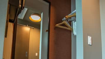 Een hal met een spiegel die een lift, een kapstok en een lamp weerspiegelt.