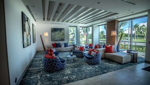 A spacious living area with a large window, a ceiling with wooden slats, and a mix of seating options including bean bags and sofas. - Hilton Garden Inn West Palm Beach I95 Outlets (West Palm Beach)