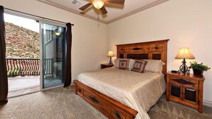 A bedroom with a bed, a ceiling fan, a nightstand, and a lamp.