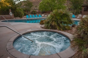 Ein Whirlpool, umgeben von einem Pool, Liegestühlen und Pflanzen.