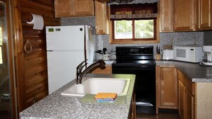 A kitchen with wooden cabinets, a refrigerator, a stove, a sink, and a window with a curtain. - Peace, Privacy and a Pontoon!! No steps in home or to water! (Eagle River)