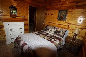 A wooden cabin bedroom with a bed, dresser, and a painting on the wall. - Peace, Privacy and a Pontoon!! No steps in home or to water! (Eagle River)