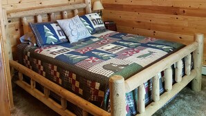 A wooden cabin room with a bed, a ceiling fan, and a window with a view of the outdoors. - Peace, Privacy and a Pontoon!! No steps in home or to water! (Eagle River)
