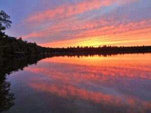 A calm lake reflecting a sunset with a forested shoreline. - Peace, Privacy and a Pontoon!! No steps in home or to water! (Eagle River)