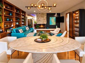 Een moderne woonkamer met een ronde marmeren tafel, een blauwe bank en een open haard.