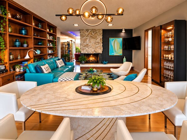 A modern living room with a round marble table, a blue sofa, and a fireplace.