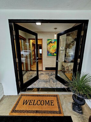 Step into a warm welcome at our hotel entrance, featuring a vibrant abstract art piece and a cozy carpeted floor.