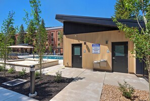 Un bâtiment doté d’une piscine, d’un espace extérieur aménagé et d’un panneau indiquant l’emplacement des installations d’hygiène personnelle.